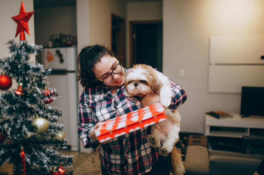 The girl holds a dog and a gift in her hands.